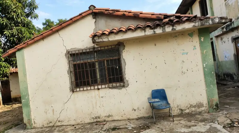 Pared de un salón de colegio público agrietada, con el ladrillo expuesto